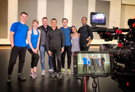 A group of people posing in front of a film camera.